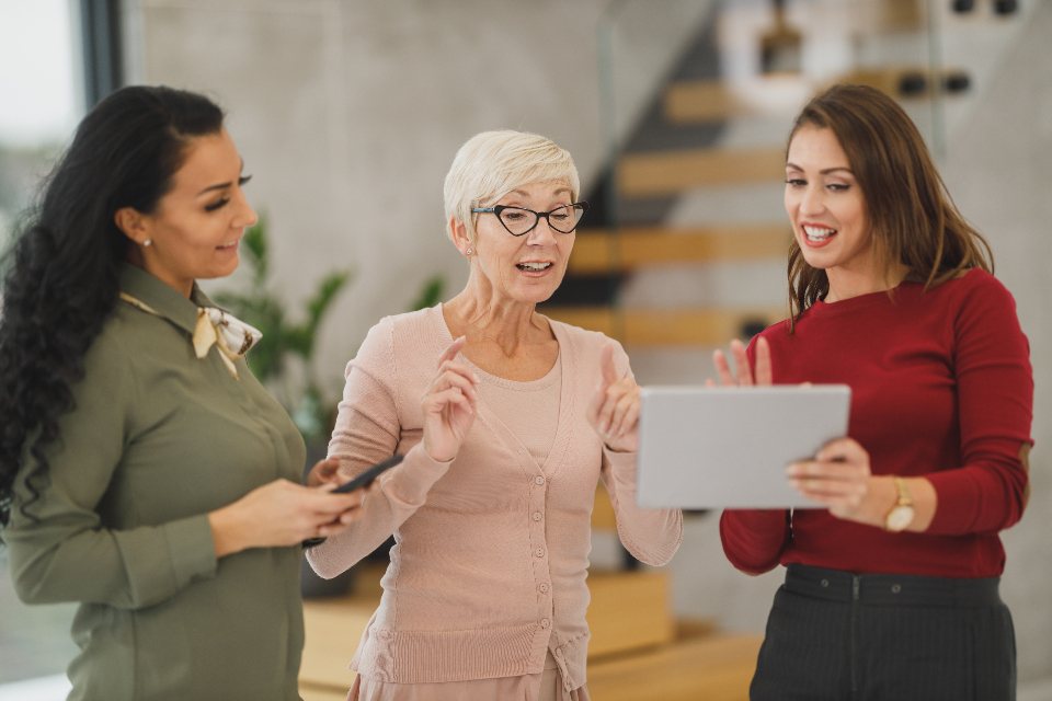 Three businesswomen in conversation over a tablet